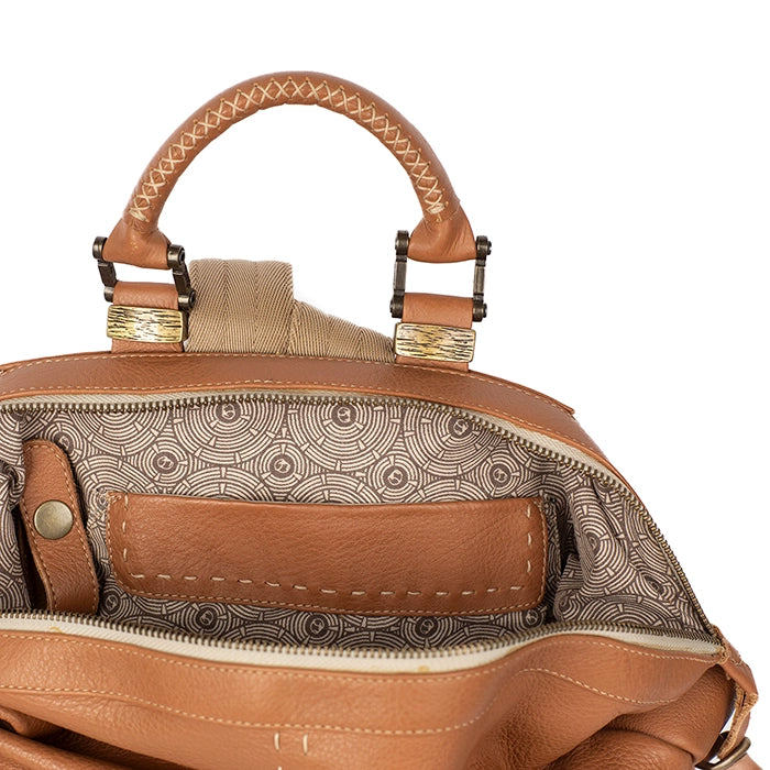 Close-up of a tan leather handbag with intricate patterns and stitching details.