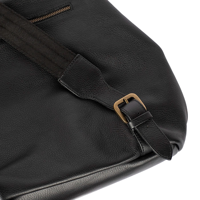 Close-up of a black leather bag with a strap and buckle on a white background