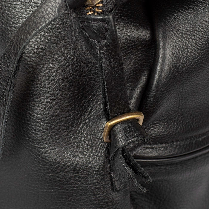 Close-up of a black leather bag with a gold buckle.