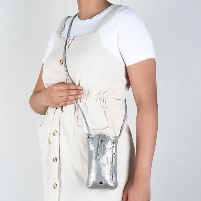 Person holding a silver cellphone pouch against a plain background